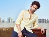 Kartik Aaryan Top Grossers
Handsome man with styled hair and beard wearing a light yellow shirt, posing on a rooftop with city skyline in the background, promoting inside box office and movie industry insights.