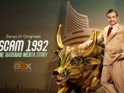 Scam 1992: Harshad Mehta Story – Episodes, Cast And Where To Watch Sonny Liv Originals Scam 1992 The Harshad Mehta Story Promotional Poster, Showcasing A Man In A Beige Suit Standing Beside A Large, Golden Bull Statue With A Cityscape And Building In The Background.