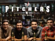 The Latest Tvf Pitchers Web Series 2022 Review A Group Of Four Men Sitting At A Bar With Bottles Of Kingfisher Beer In Front Of Them, Smiling And Enjoying A Social Moment, With A Blurred Background Of A Liquor Store.