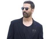 Akshay Kumar Stylish Man Wearing Black Blazer And Sunglasses With Reflective Lenses, Set Against A Plain White Background, Representing Modern Cinema And Entertainment Industry.